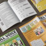 Full voice music workbooks on a wooden table
